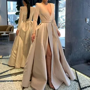 Elegant champagne gold long sleeve V-neck evening gown with a high slit and waist belt