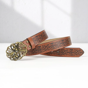 Detail of vintage brown leather belt with leaf embossing and a bee buckle with crystals