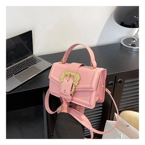 Pink crossbody square bag detail showing golden lion head hardware lock and leather texture