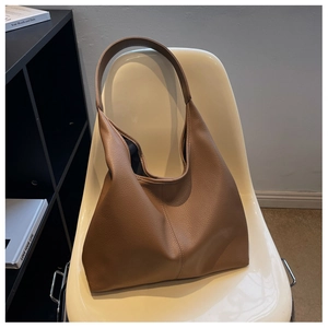 Detail of a brown lychee pattern PU leather tote bag placed on a minimalist chair