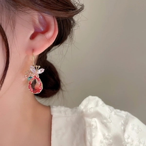 Détail d'un mannequin portant des boucles d'oreilles papillon dorées et zircon rouge