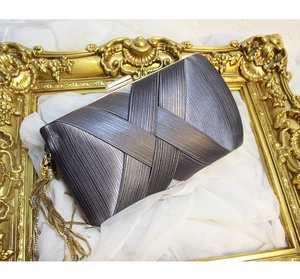 Detail of grey pleated satin evening clutch bag with gold tassel and metal frame hardware