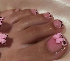 Macro shot of press-on toe nails with leopard french tips and 3D pink bow accent