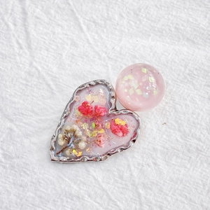 Handmade resin heart hair clip with pink dried flowers and golden glitter on white linen