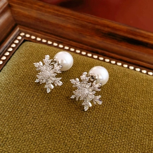 Sparkling zircon snowflake pearl earrings on vintage green velvet display