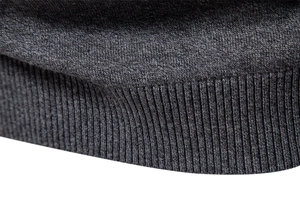 Close-up of charcoal grey knit sweater showing ribbed cuffs and premium fabric texture
