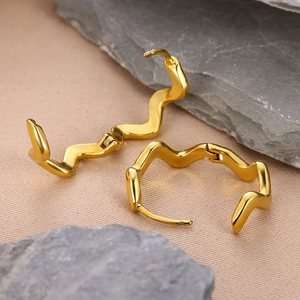 Minimalist gold wavy geometric hoop earrings with zircon on a textured stone background