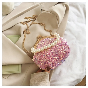 Detail of pink sequin crossbody bag with pearl handle and golden chain strap