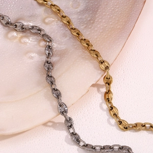 Detail of gold and silver coffee bean link bracelets on a wet shell texture