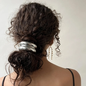 Minimalist silver stainless steel hair tie cuff shown on model with dark curly hair