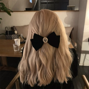 Detail of black velvet rose bow hair clip worn on elegant wavy blonde hair