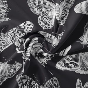 Detail of black silk fabric with white butterfly print showing satin texture and folds