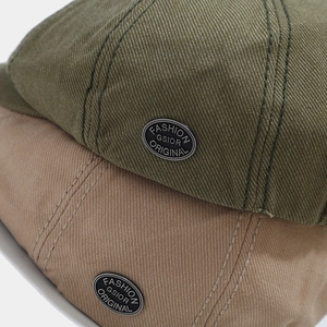 Detail of heavy twill cotton newsboy cap with premium metal badge on olive and khaki fabric