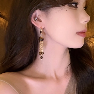 Elegant long tassel earrings with golden chains and tiger eye beads on female model