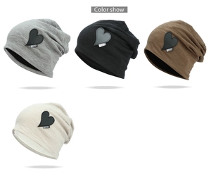 Detail view of four colors of knitted beanies with black heart leather patch accents