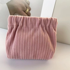 Detailed close-up of pink corduroy lipstick pouch with a flexible spring squeeze closure