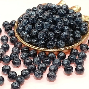 Macro view of 10mm deep blue crackle glass beads on a golden tray for DIY jewelry