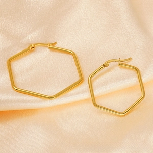 Détails des boucles d'oreilles hexagonales en or poli sur fond de soie de couleur champagne