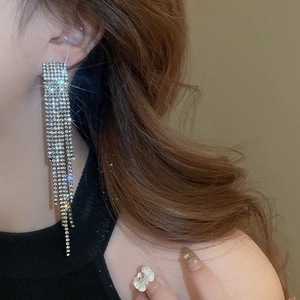 Close-up of model wearing silver long tassel earrings with sparkling rhinestones