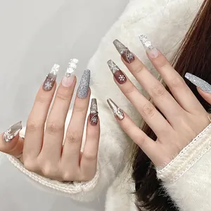 Détail de faux ongles longs avec flocons 3D, perles et paillettes argentées brillantes