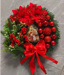 Detail of Christmas wreath with red poinsettia flowers and Nativity scene card