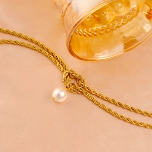 Detailed close-up of golden rope chain necklace featuring a white pearl pendant