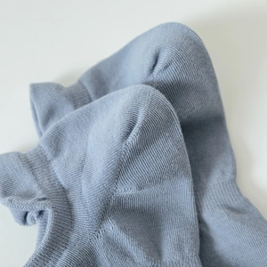 Macro shot of light blue cotton mesh socks showing precise heel stitching and knit texture