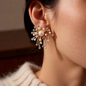 Detailed close-up of 18k gold plated firework earrings with pearls and zircon on a model