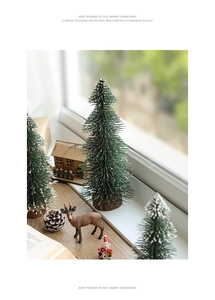 Close-up of mini snow-flocked Christmas trees on wooden bases with festive decor