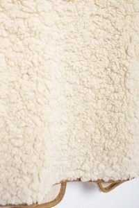 Close-up of beige faux shearling fleece fabric texture with brown hem border detail