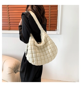 Quilted beige puffer hobo bag shown on shoulder in a warm lifestyle interior scene
