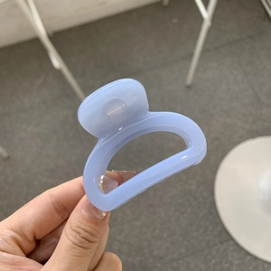 Detail of light blue resin hair claw clip with a transparent finish and arc design