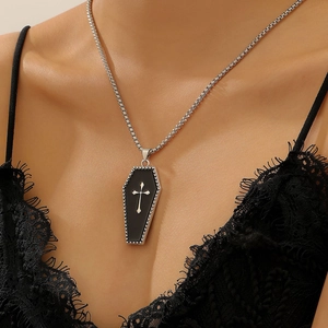 Macro shot of gothic coffin pendant with silver cross on black enamel and lace outfit