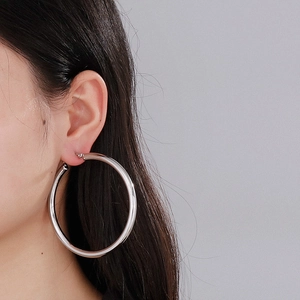 Minimalist silver titanium steel hoop earring worn by model on plain background