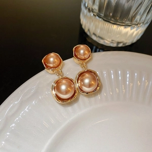 Gros plan de boucles d'oreilles vintage en or avec perles ambre sur plateau blanc