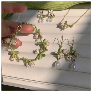 Detailed jewelry set featuring lily of the valley flowers with green leaves and pearls
