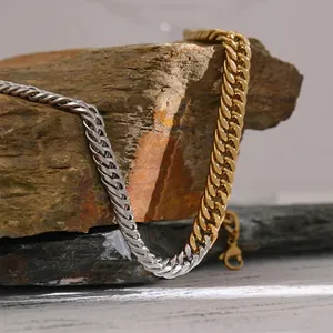 Two-tone silver and gold stainless steel Cuban link necklace on a rustic rock display