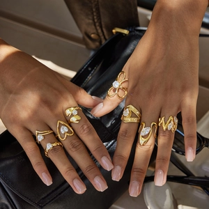 Anillos clásicos de titanio dorado con circonitas usados en varios dedos de la mano