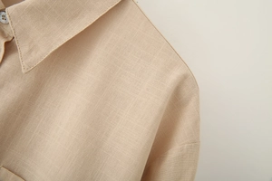 Detailed close-up of beige linen shirt collar showing texture and stitching quality