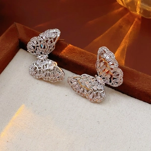 Macro shot of silver butterfly stud earrings with micro-set zircons on wooden tray