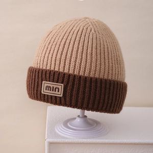 Detail of knit beanie featuring contrast stitching and min letter patch on folded cuff