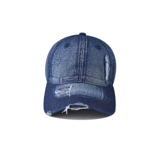Close-up of distressed dark blue denim baseball cap with heavy ripped hole details