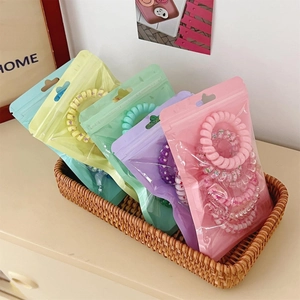 Detail of gradient macaron phone cord hair ties in frosted bags inside a woven basket