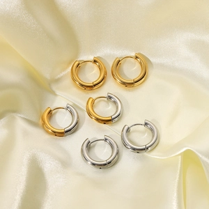 Detailed shot of gold, silver, and two-tone hoop earrings on soft beige silk fabric