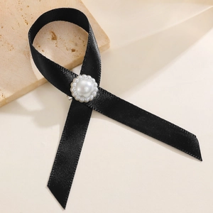 Gros plan détaillé d'une broche en ruban de satin noir ornée d'une perle centrale chic