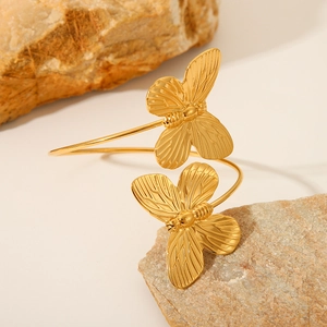 Elegant gold stainless steel butterfly open cuff bracelet displayed on natural stones