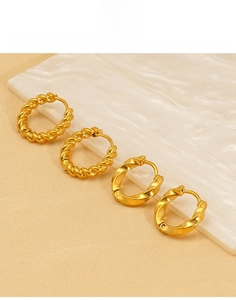 Detail of gold titanium steel hoop earrings featuring twisted and spiral textured designs