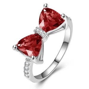 Macro detail of silver bow ring with triangle red gemstones and zircon accents