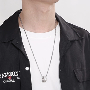 Close-up of a silver hip-hop style pendant necklace with pavé crystals worn on a model