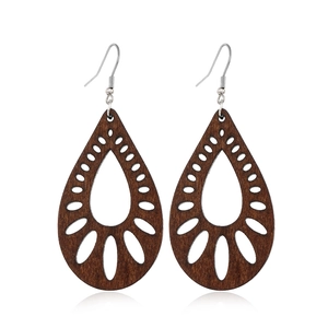 Macro shot of brown hollow-out wooden teardrop earrings with intricate geometric patterns